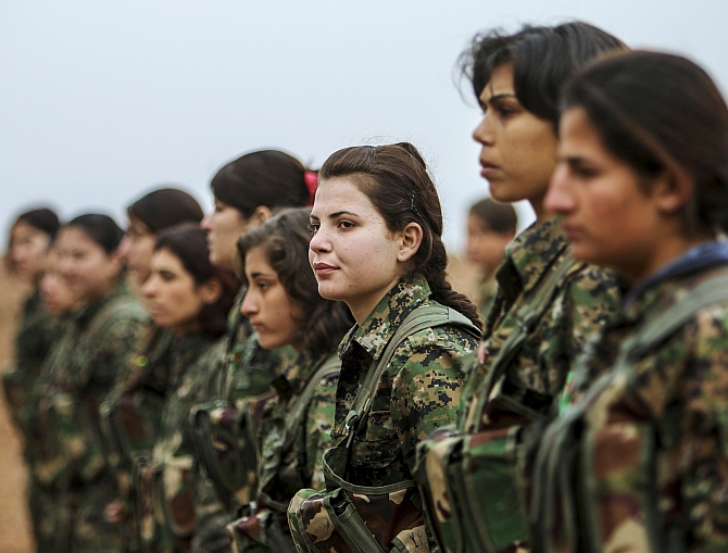 Female fighters of the Kurdish People's Protection Units stand at attention at a military camp in Ras a-Ain